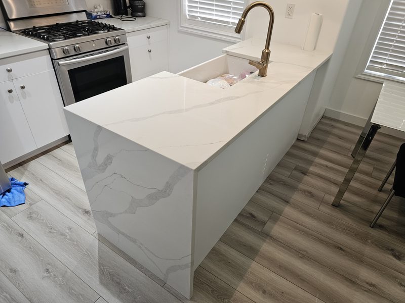 White shaker kitchen with waterfall quartz island by Monarch Cabinets